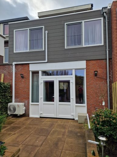 Moderne twee-verdiepingen woning met grote ramen en een terras.